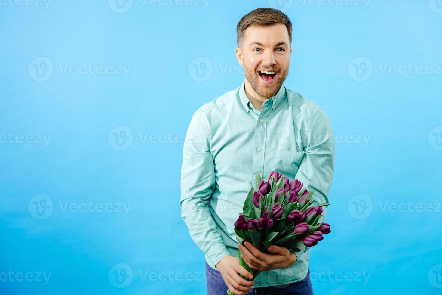 Man is holding bouquet of purple tulips on dark background. Spring flowers for Mother's Day, International Women's Day, birthday photo