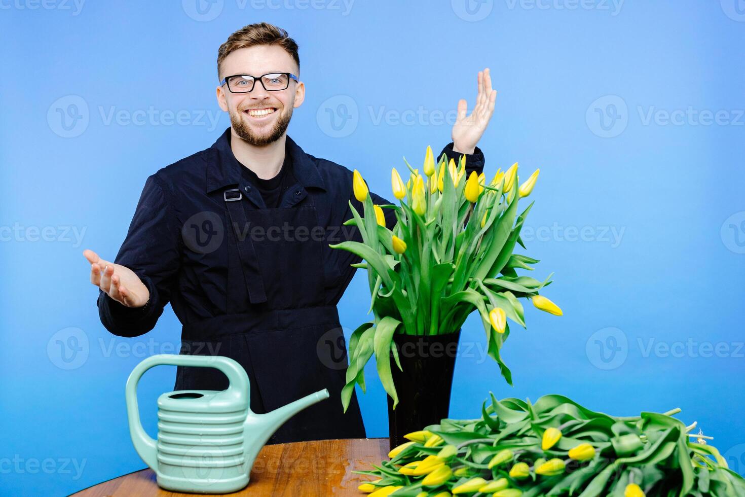 Man flower shop manager standing in apron in floral shop. Man working a with tulips in flower shop. photo