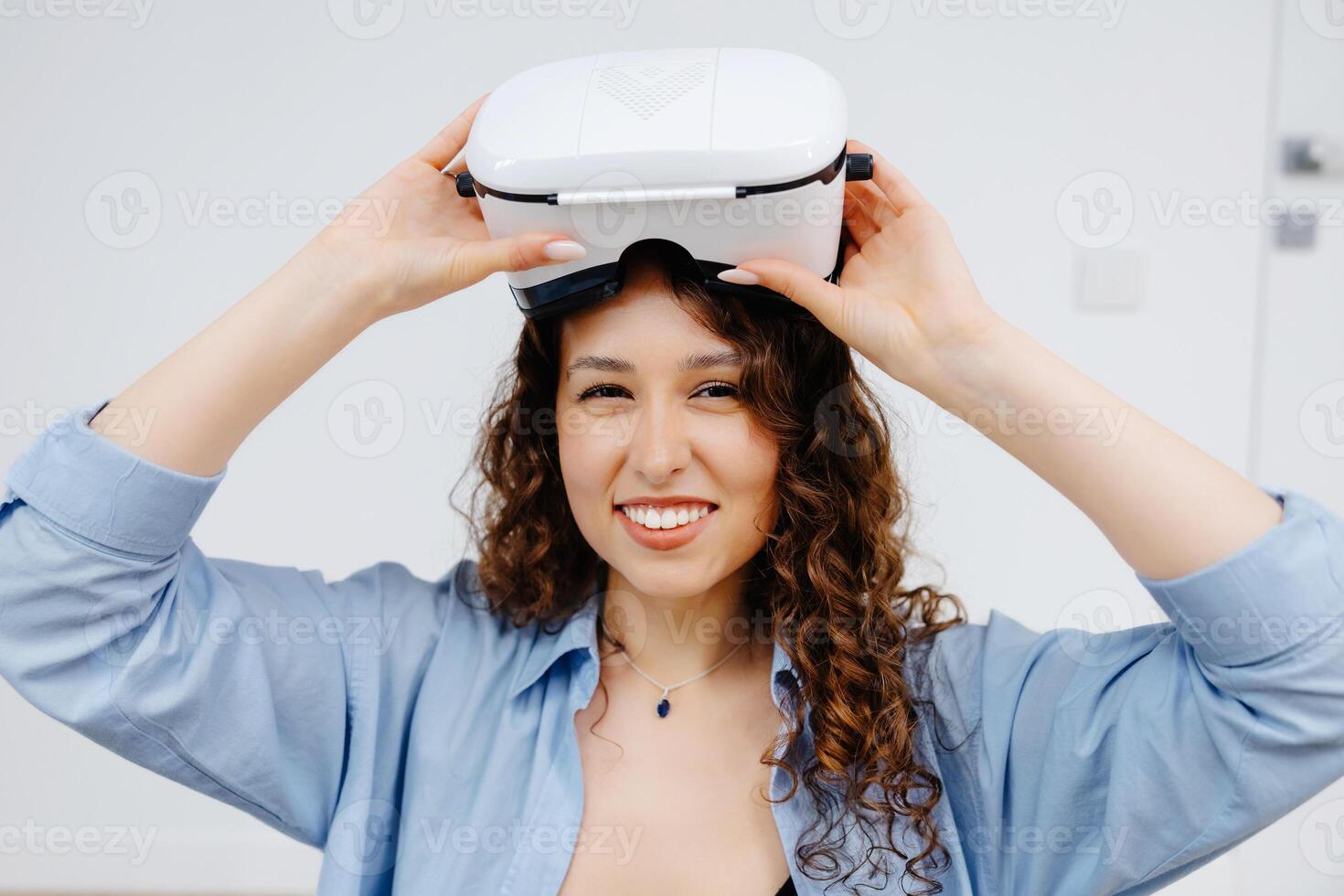 Young woman in VR glasses using modern technology creating room design, moving hands in air, sitting in new apartment during renovation. Virtual reality and repair concept photo