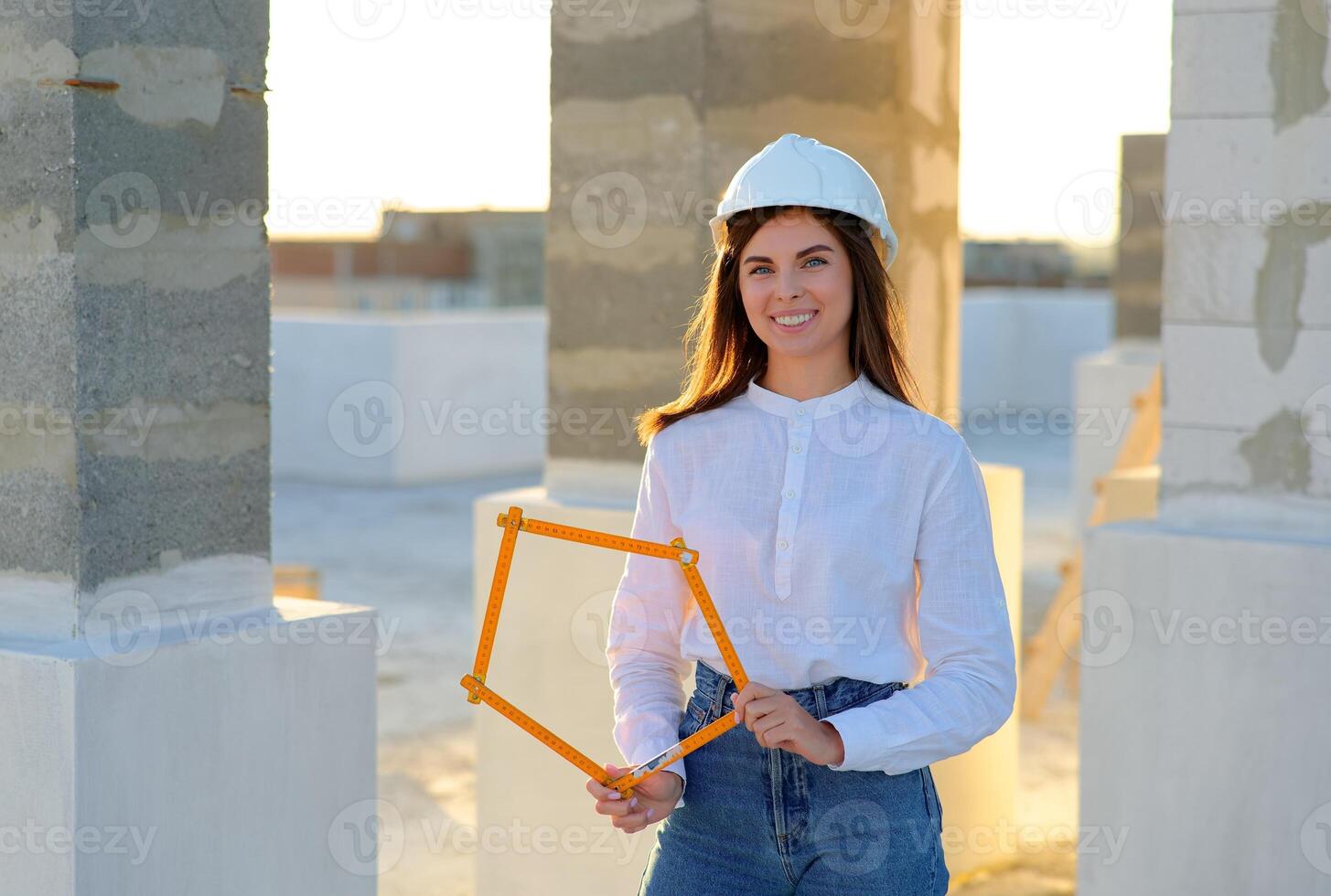 Female architect holding folding ruler on construction site at sunset. photo
