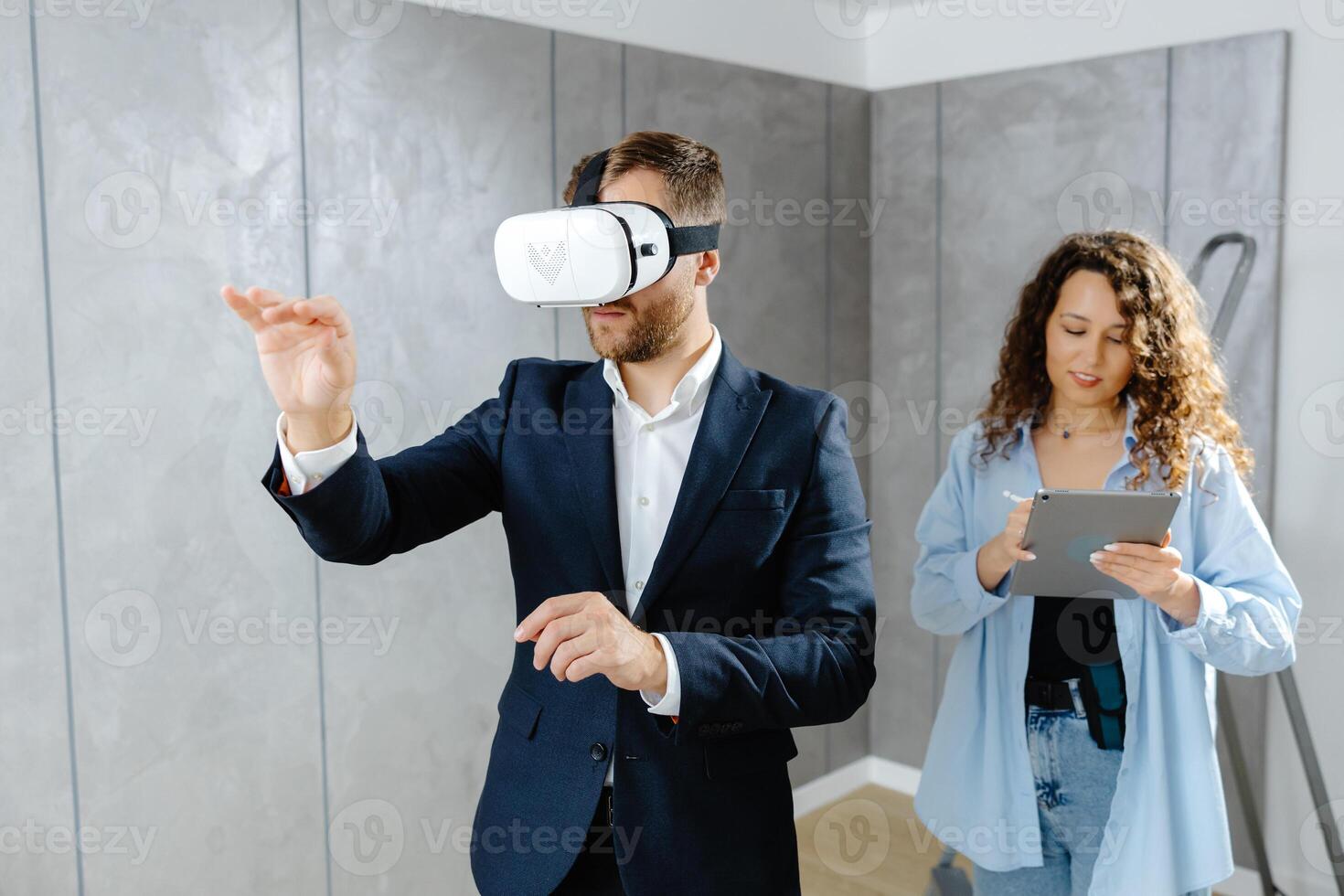 Man client wearing VR glasses imagining future interior standing with designer at the construction site. photo