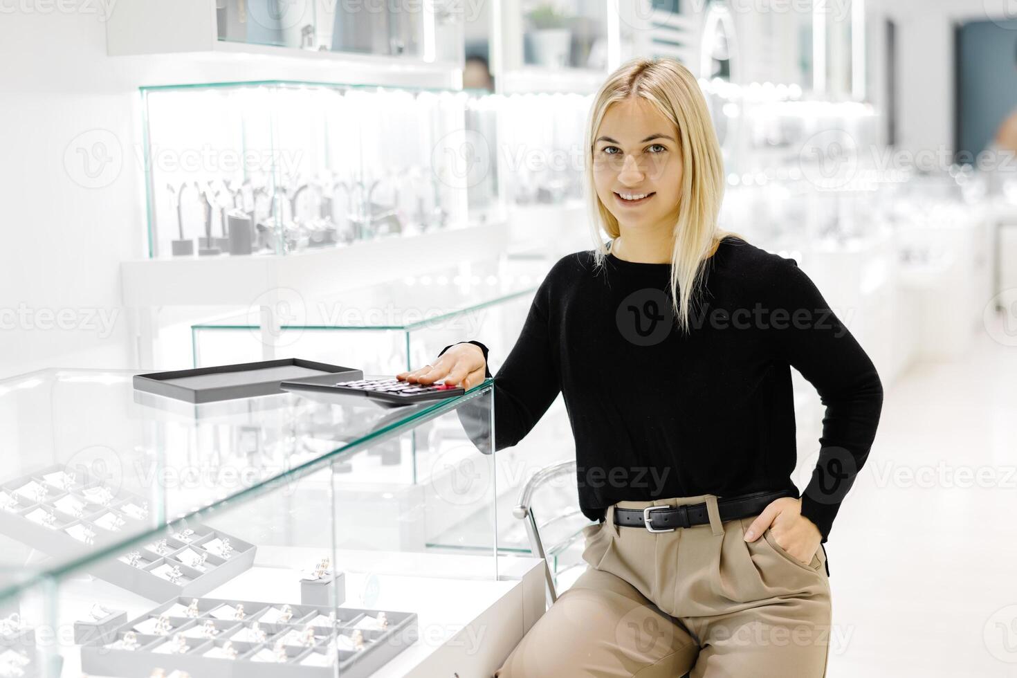 Saleswoman calculating price using calculator in jewelry shop photo