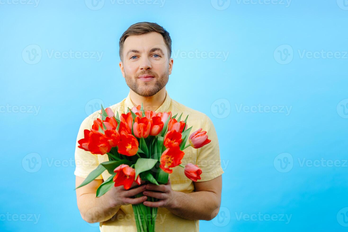 Man is holding bunch of red flowers. photo