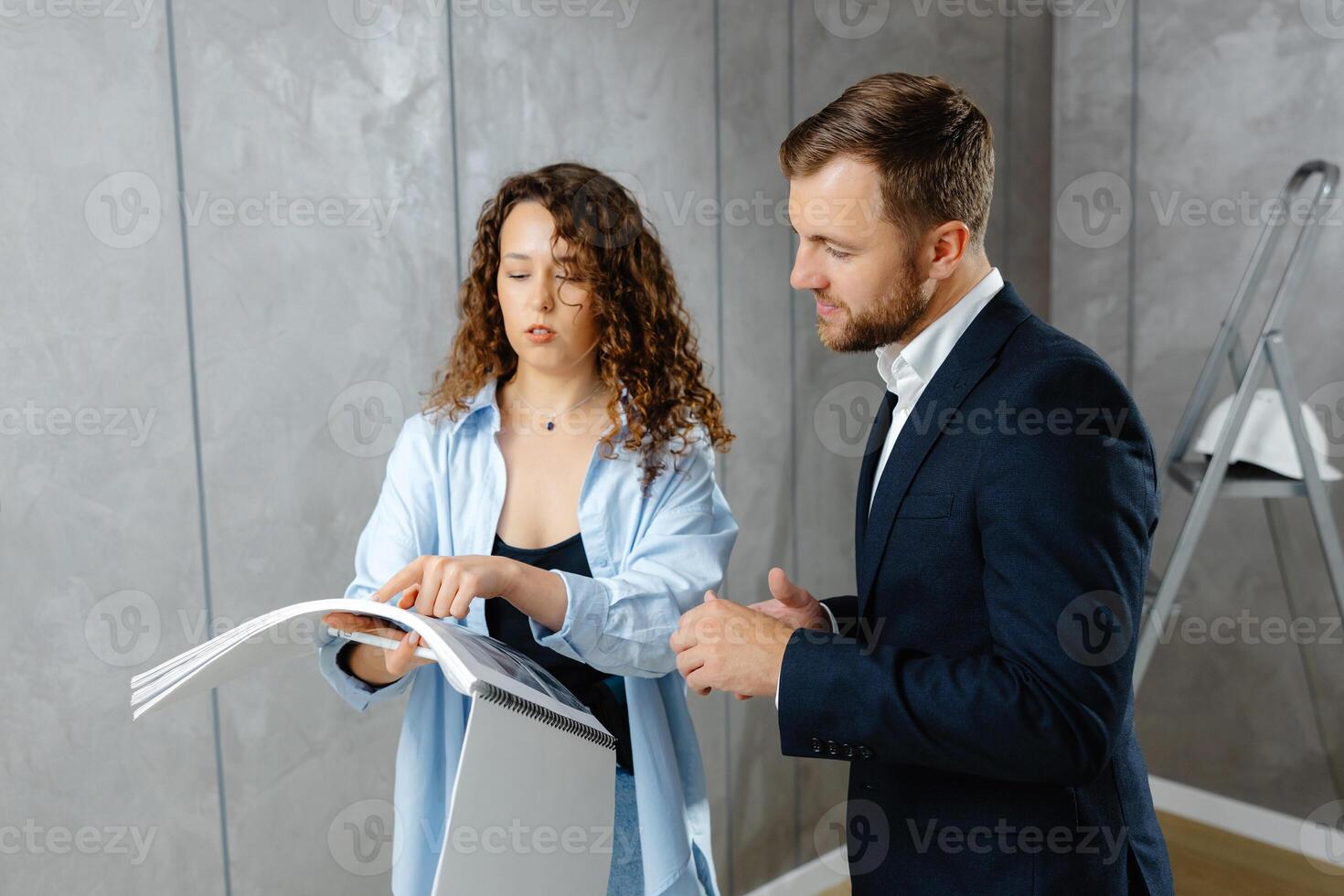 A young designer discusses the plans and design of the room with the customer. The concept of repair on a modern design. photo