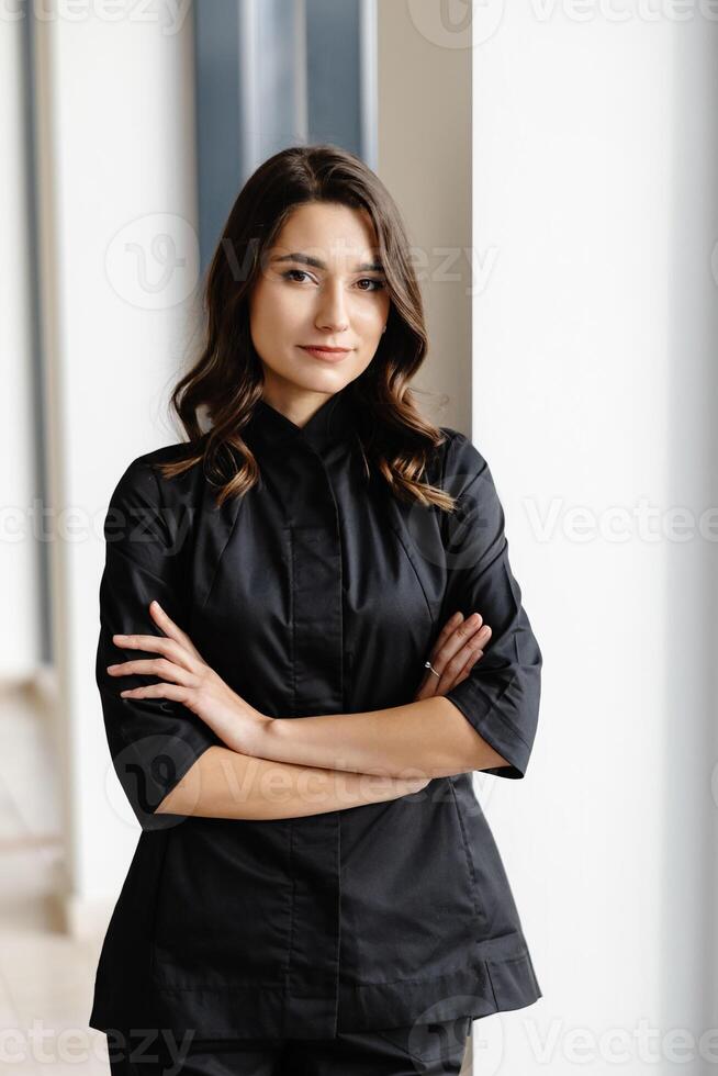 Young female doctor is standing in a hospital hall and looking at the camera. photo