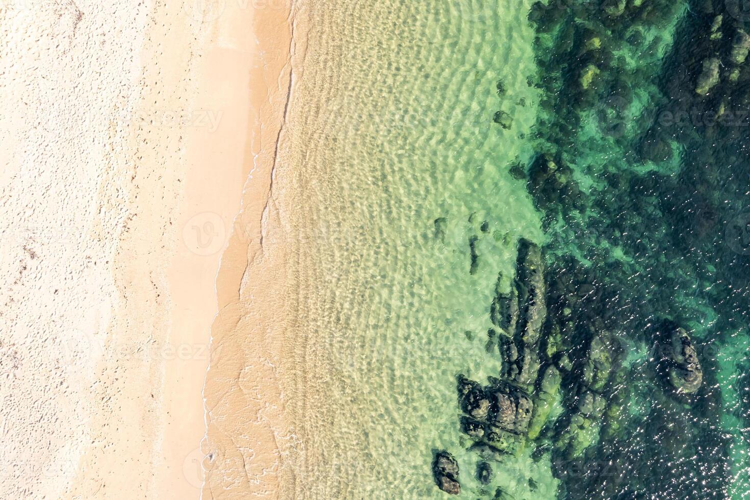 drone shot of sandy beach merging with rocky ocean floor. Aerial drone top down view. Background beach concept texture photo