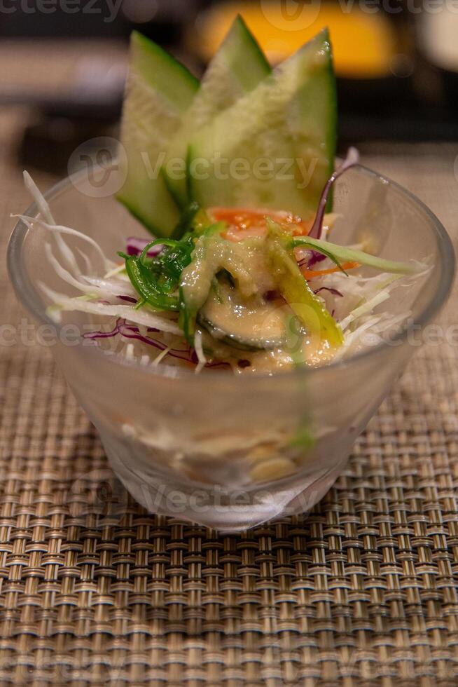 A bowl of food with a cucumber and a piece of carrot photo