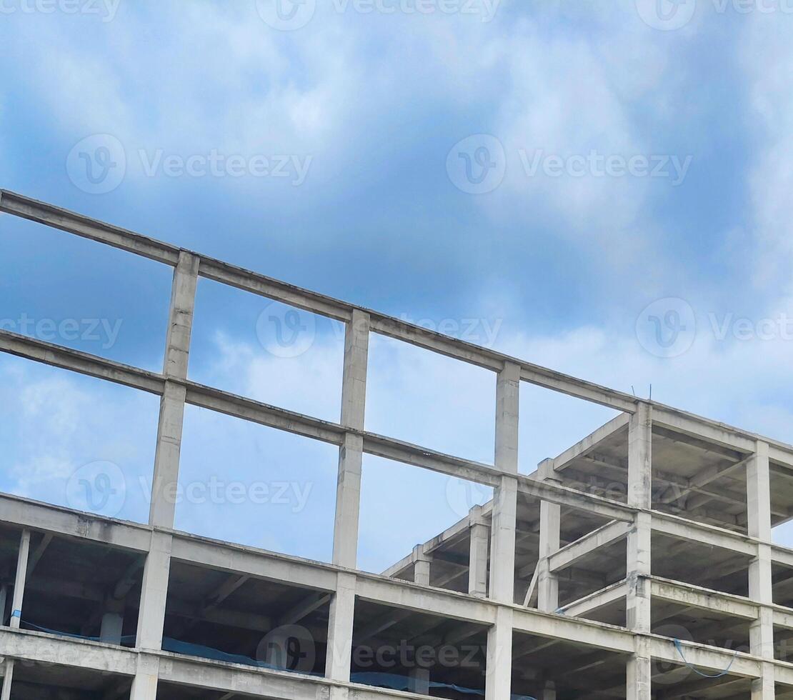 Unfinished Concrete Building Structure. A low-angle view of an unfinished concrete building structure against a cloudy sky photo