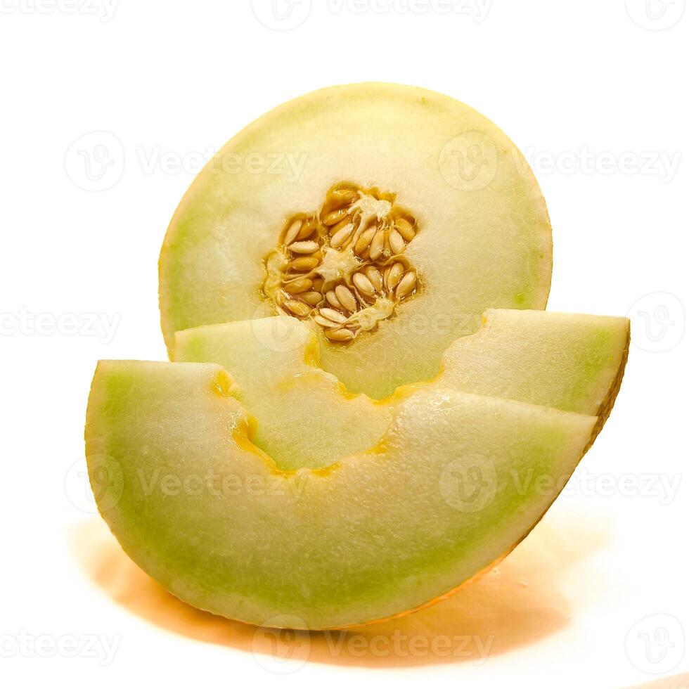A fresh honeydew melon cut in half, revealing its juicy flesh and seeds, with a few slices removed. The fruit is vibrant green rind contrasts with its soft, sweet interior. photo