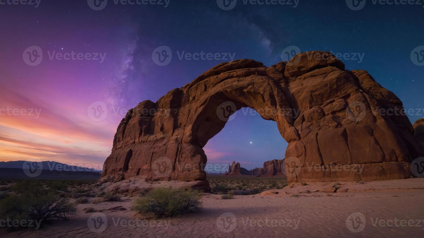 A stunning natural arch illuminated by twilight and the Milky Way in a desert landscape. photo