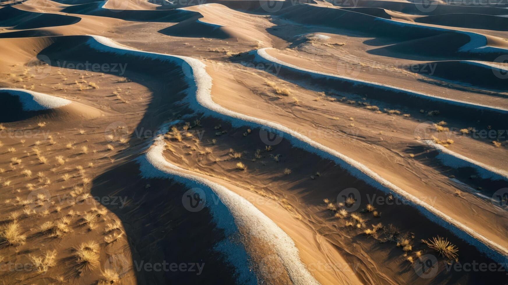 Aerial view of undulating sand dunes with sparse vegetation in a desert landscape. photo