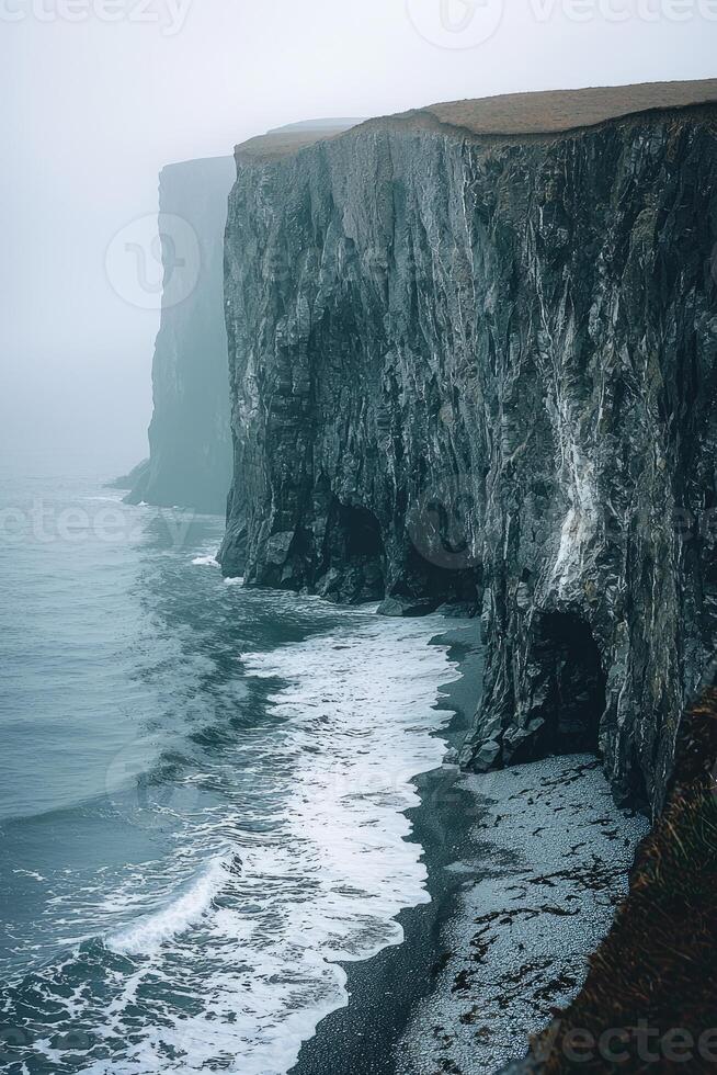 Dramatic coastal cliffs meet ocean waves on a foggy day photo