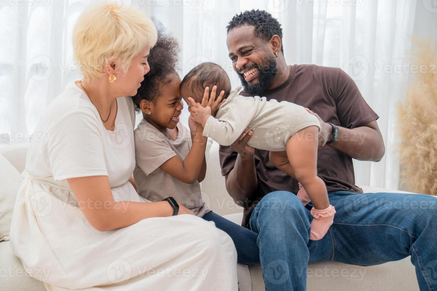 Family enjoys playful bonding time at home on a sunny afternoon with children smiling and laughing together photo