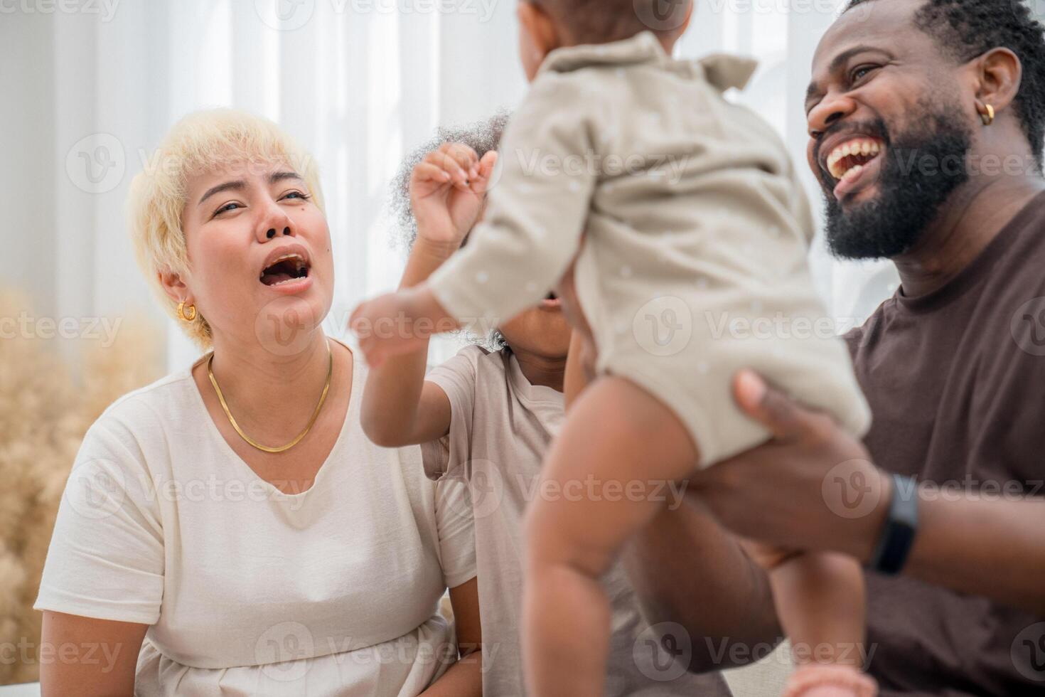 Family enjoying playful moments together while interacting with a baby in a bright and cozy indoor setting photo