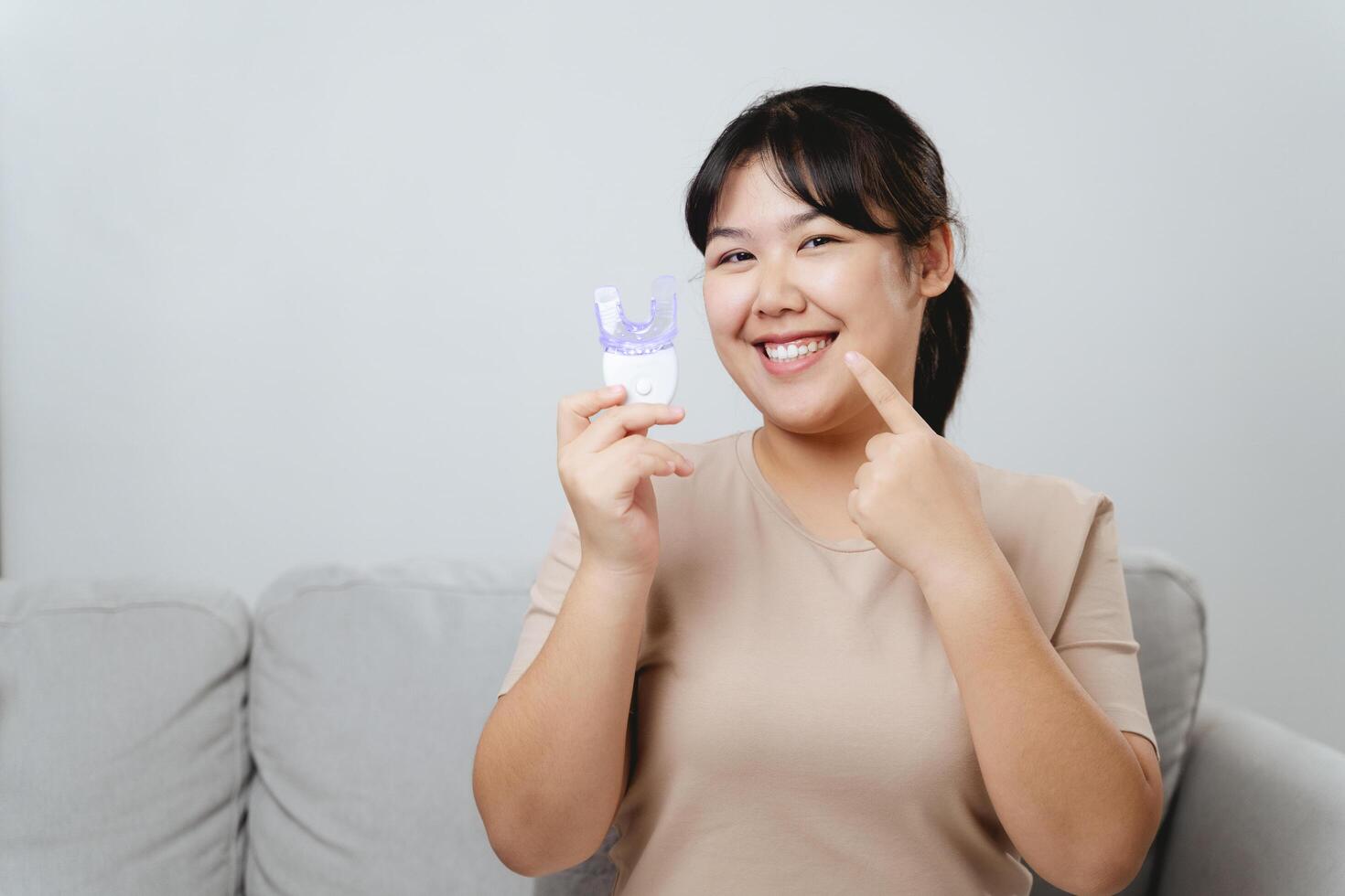 The woman She is independently whitening her teeth with a tooth whitening gadget. photo