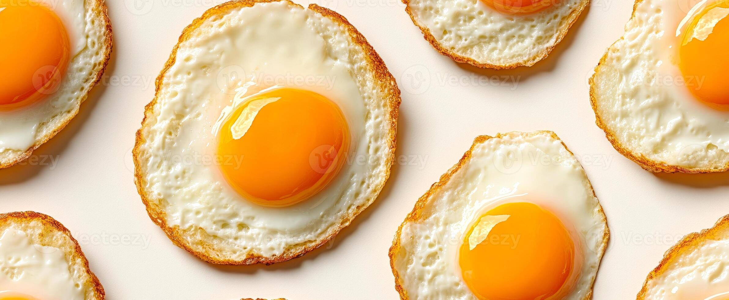 Fried eggs arranged on a light surface. Several perfectly fried eggs with bright yolks are neatly arranged on a light background for an appetizing display. photo