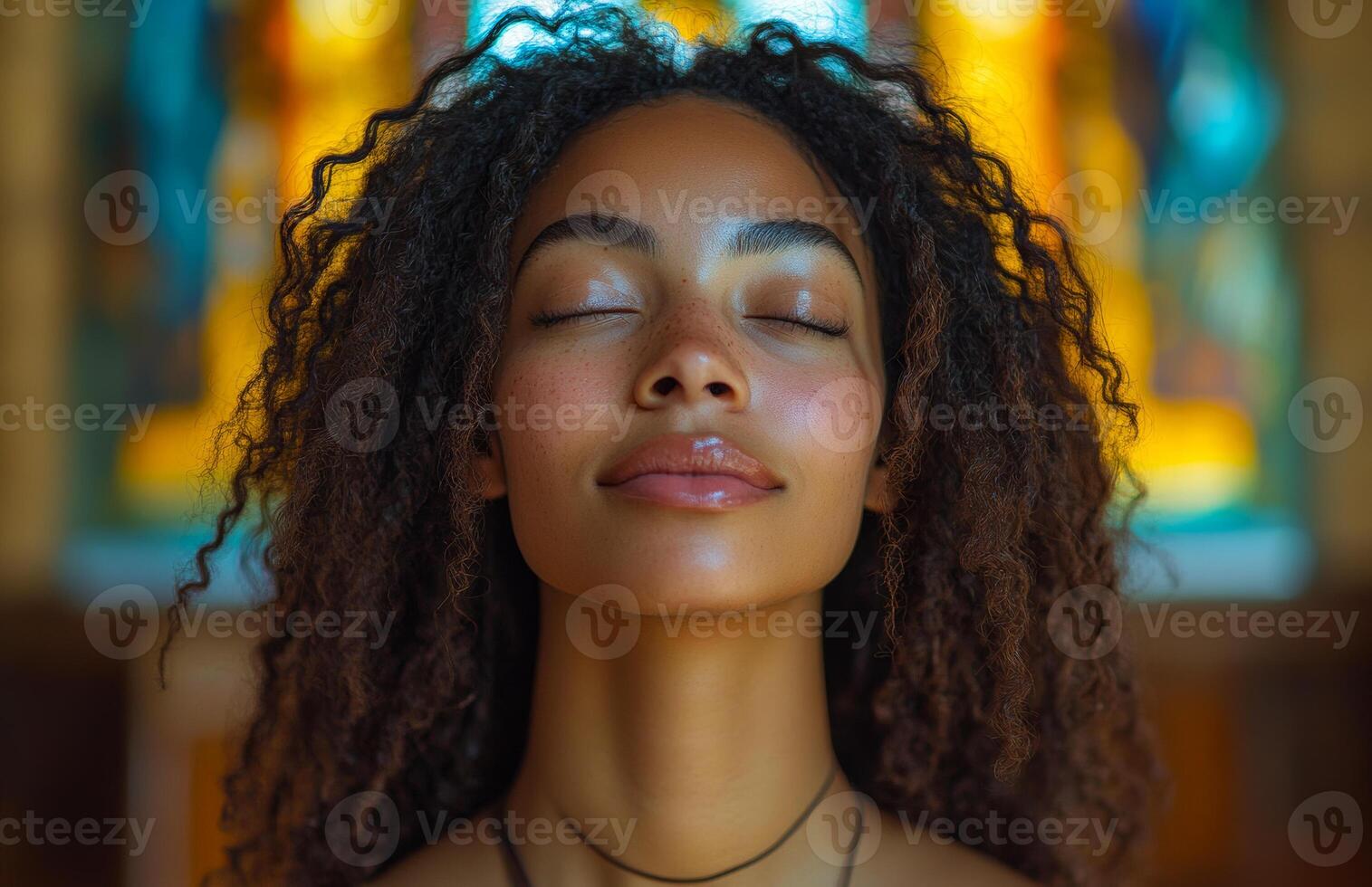 Calm reflection in a serene space. A young woman with curly hair enjoys a moment of peace, eyes closed, in a beautifully lit setting with stained glass. photo