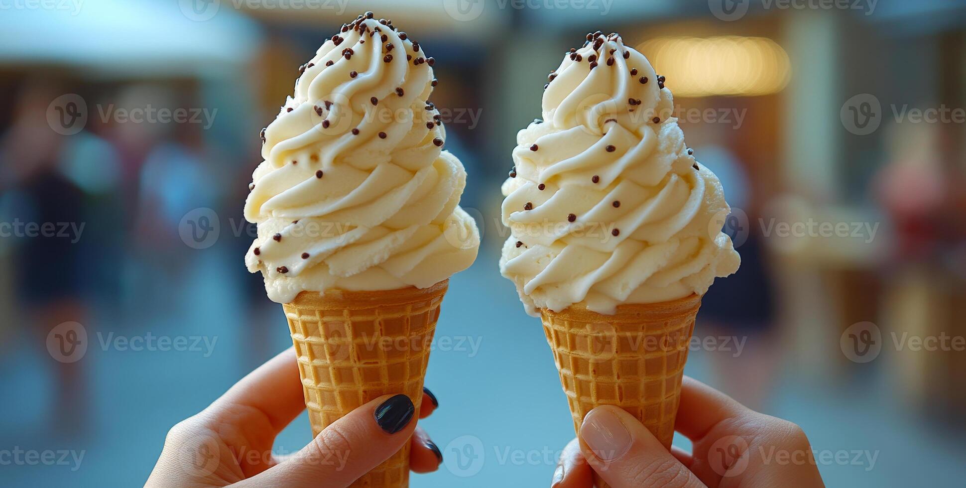 Enjoying ice cream cones on a sunny day. Two hands hold ice cream cones topped with whipped cream and chocolate sprinkles in a vibrant outdoor market. photo