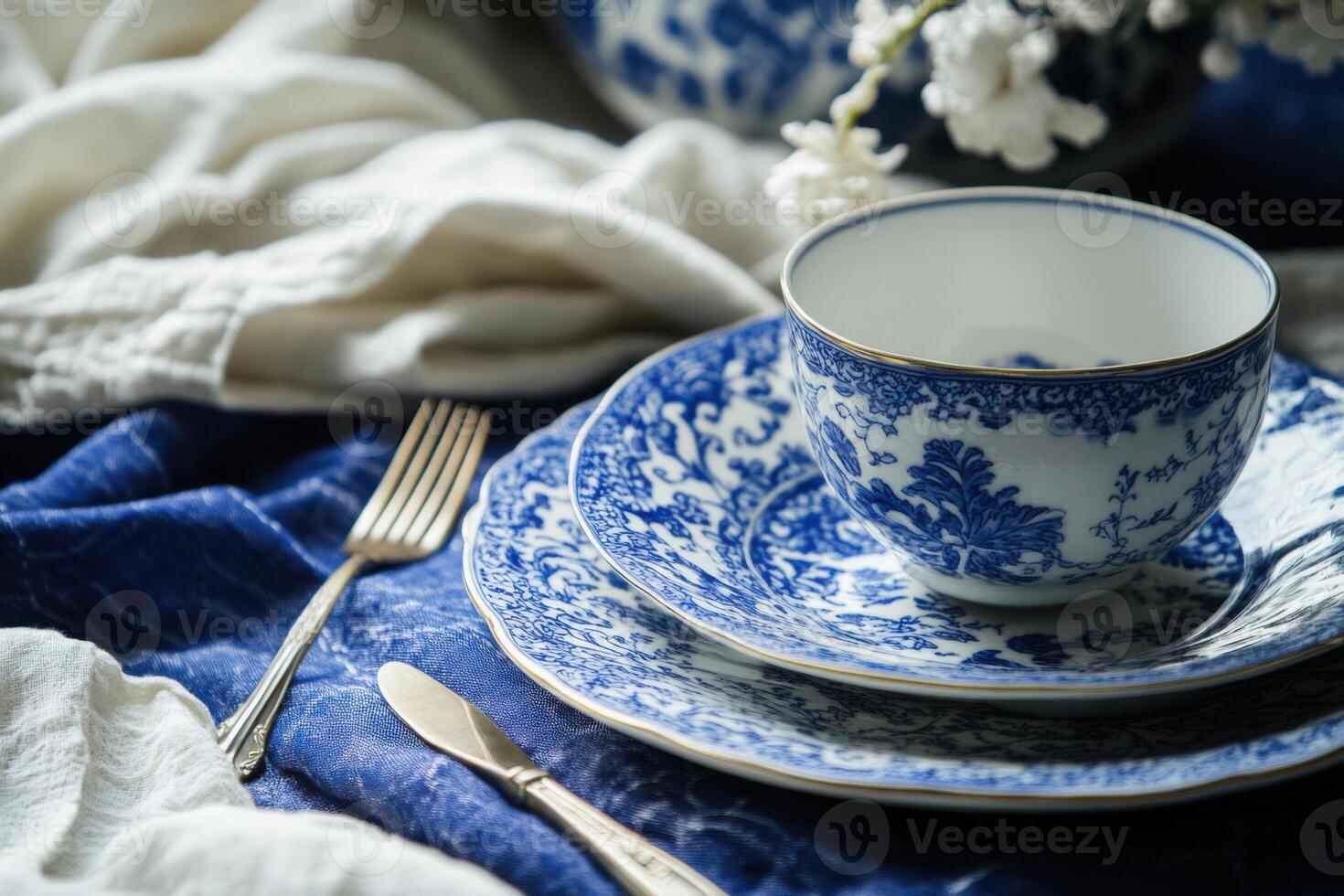 Elegant cobalt blue ceramic tableware set with teacup, plate and cutlery resting on a blue tablecloth photo