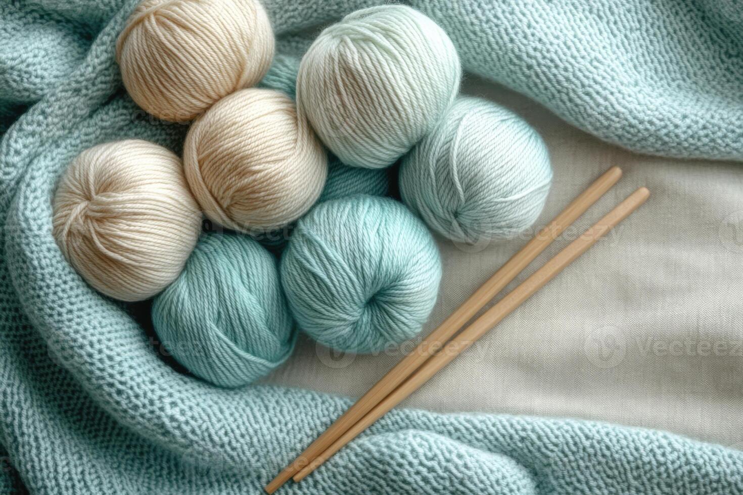 Skeins of yarn and knitting needles resting on knitted fabric photo