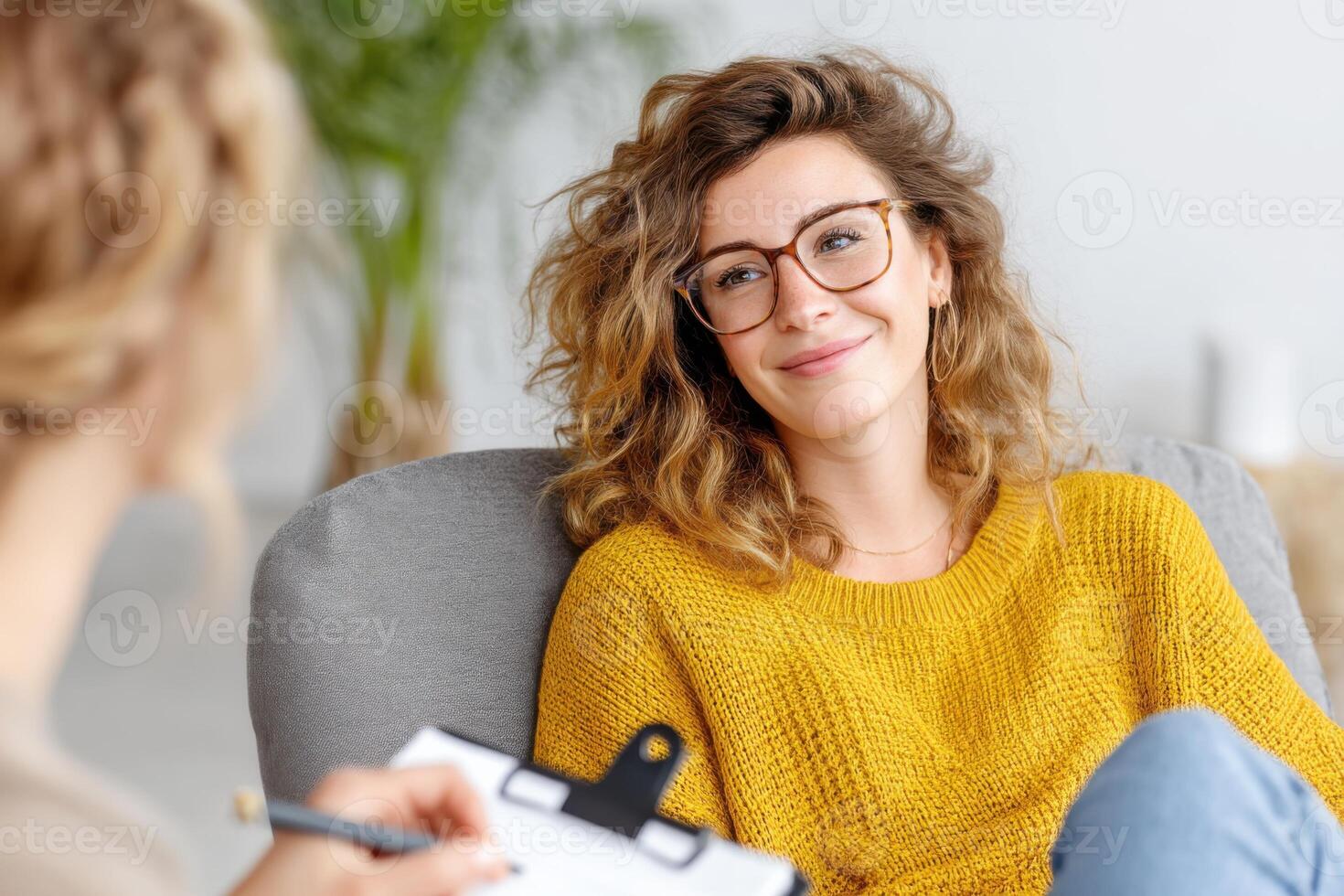 Young woman smiling during therapy session with psychologist taking notes photo