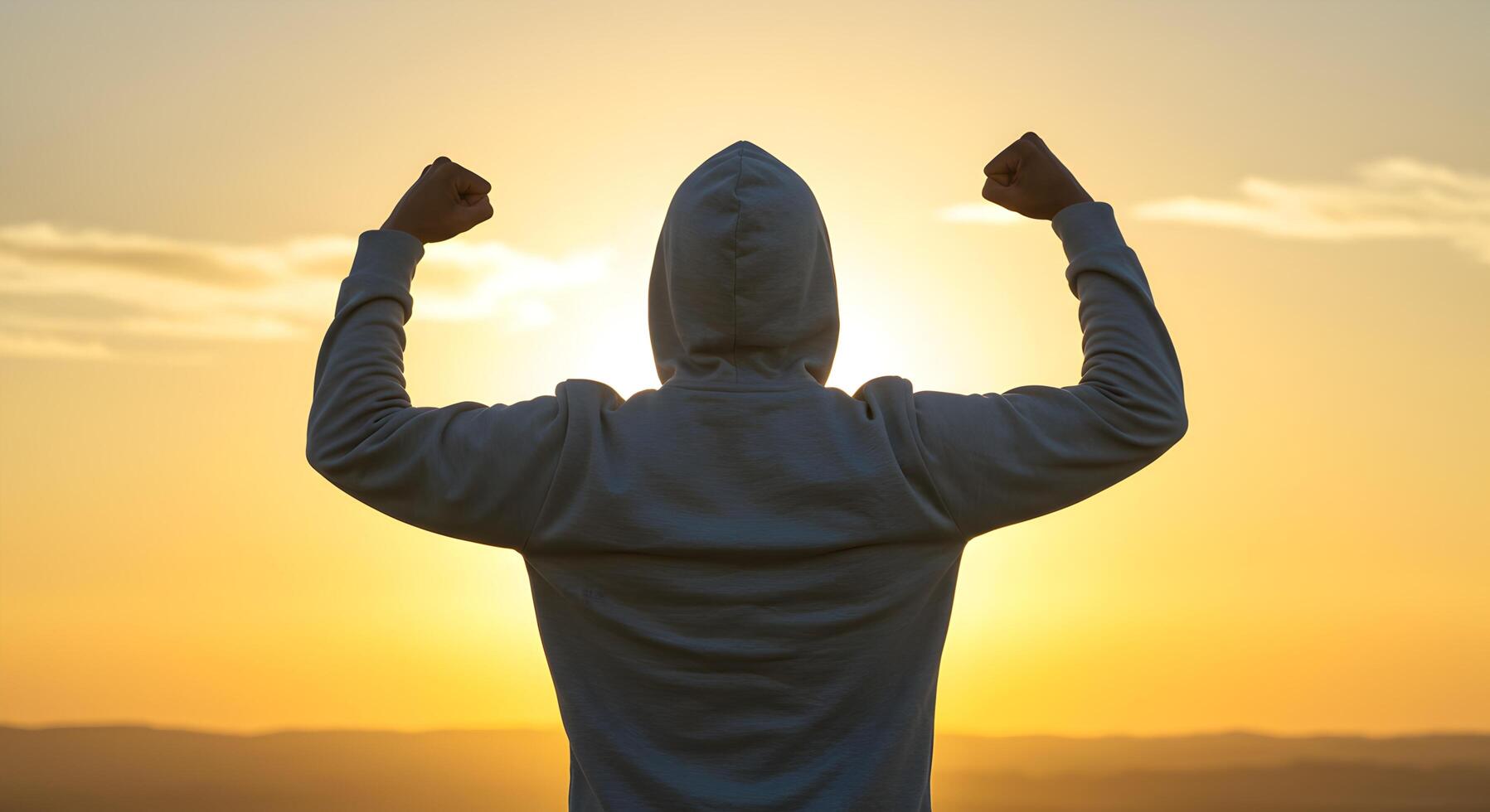 Silhouette of a person with raised fists against a golden sunset background photo