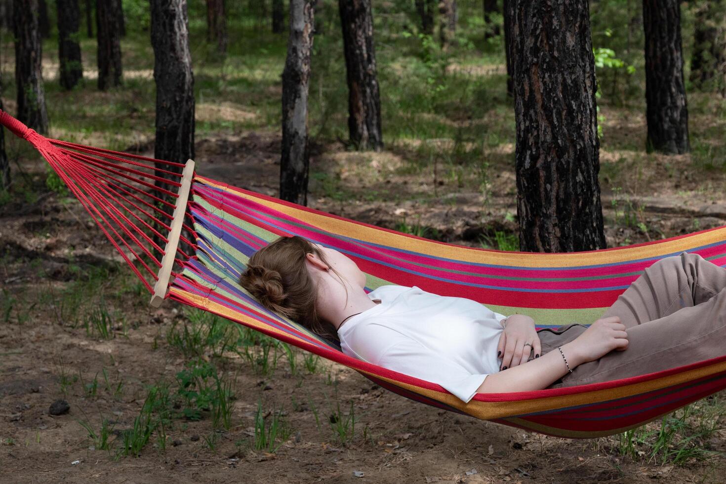 Beautiful young woman relaxing in hammock in forest. Summer scenery, a beautiful morning in the bosom of nature. The girl admires the views and nature. Breathed fresh air. Beautiful morning light. photo