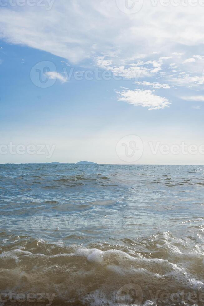 Sea waves on the beach against the blue sky with clouds photo