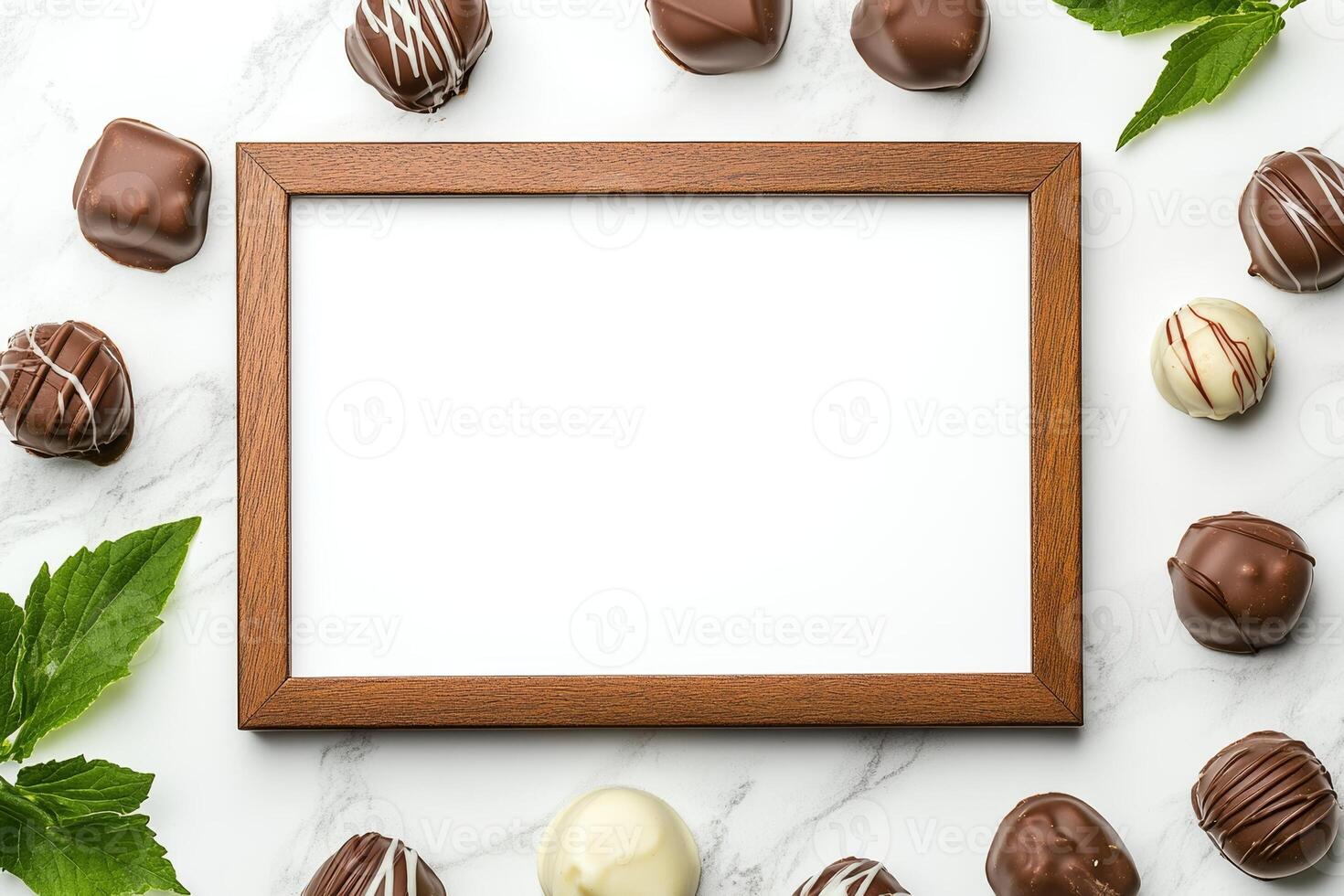 A blank wooden frame surrounded by assorted chocolates and mint leaves on a marble surface. photo