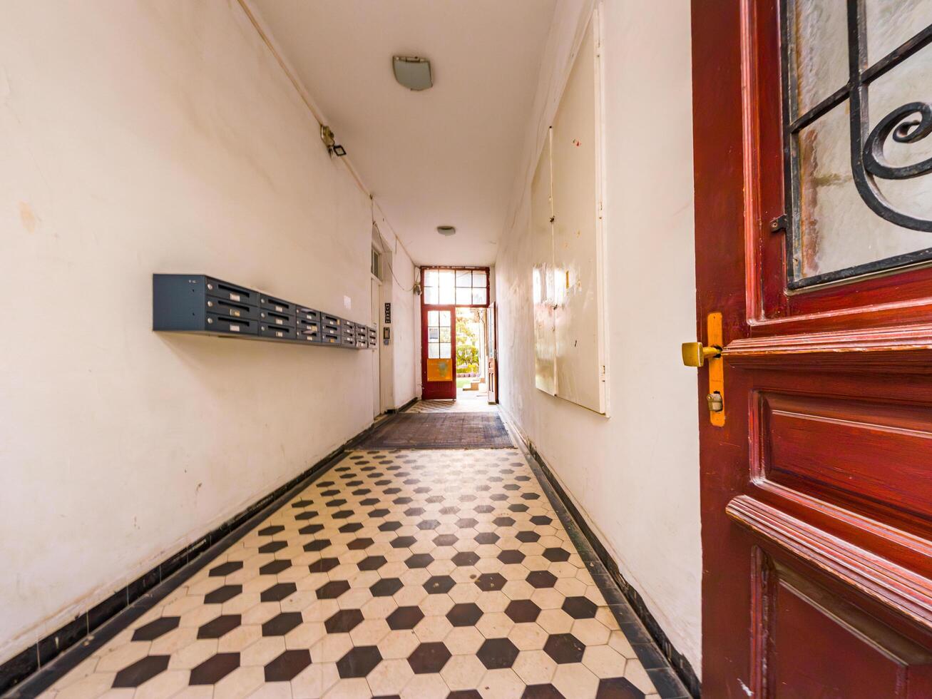 Sunlit old hallway with geometric tiles and open wooden door, evoking nostalgia and timeless charm. photo