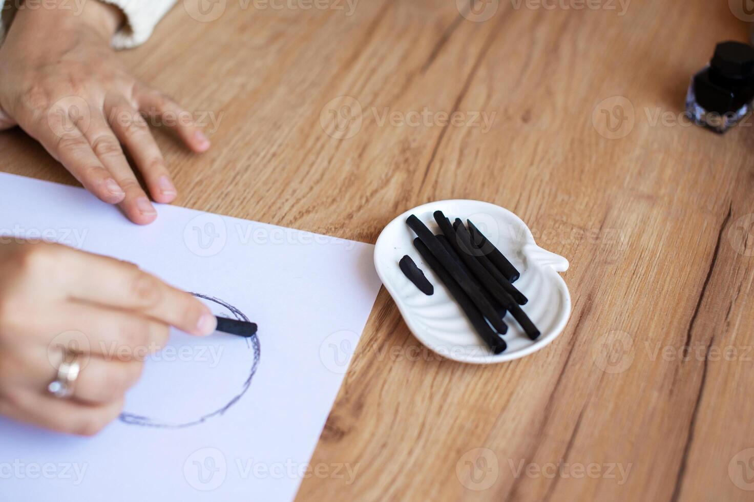 Woman Practicing Calligraphy with Black Ink and Nibs on White Paper. photo