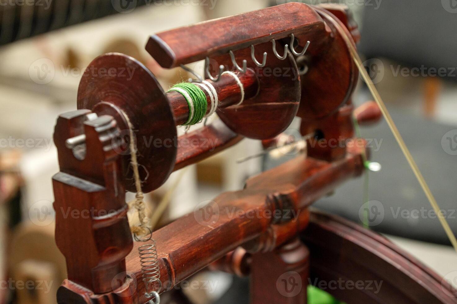 Distaff Day Traditional wooden spinning wheel with green yarn in workshop photo