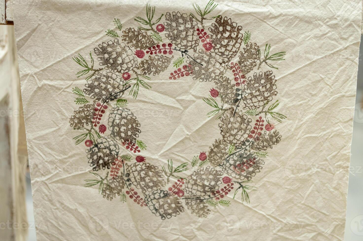 Rustic pine cone and berry wreath on textured fabric background photo
