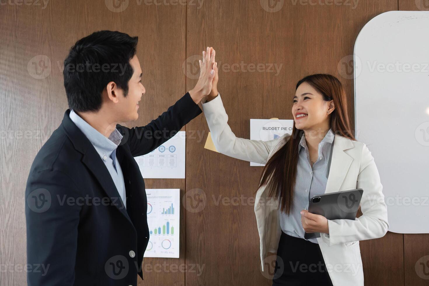 Collaboration and Team Building. Colleagues share a celebratory moment with a high five after successfully completing their presentation. photo