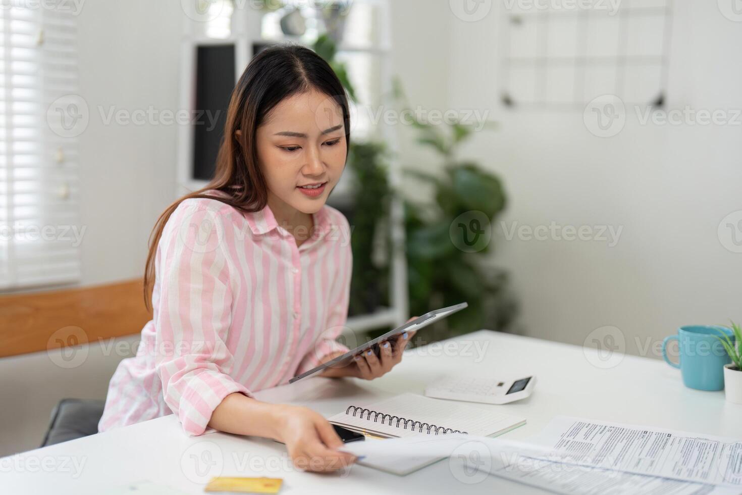 Task Management and Home Office. A woman balances her schedule while reviewing important documents in her workspace. photo