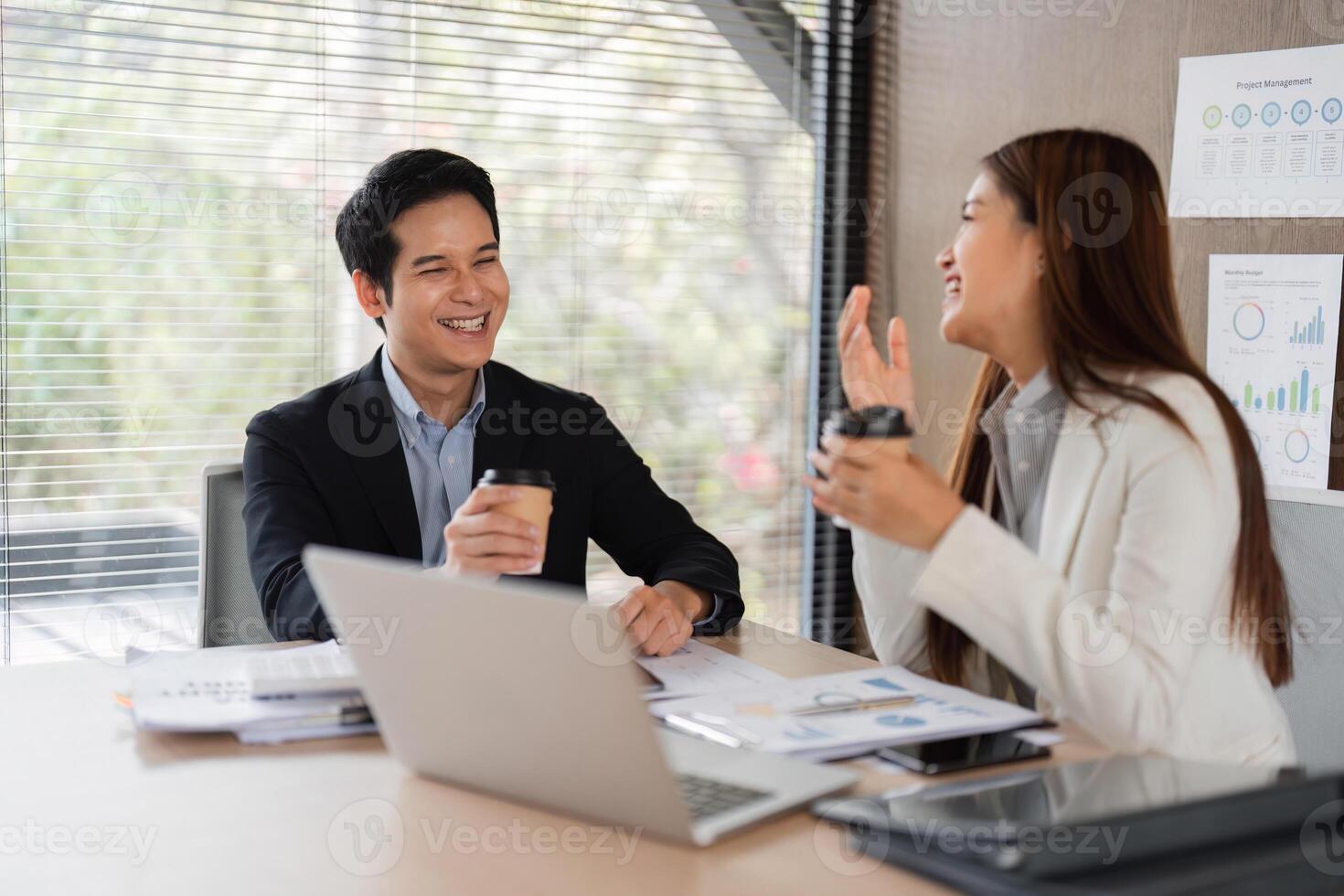 Building Relationships and Enjoying Coffee. Two colleagues share a moment of laughter and coffee in the office. photo