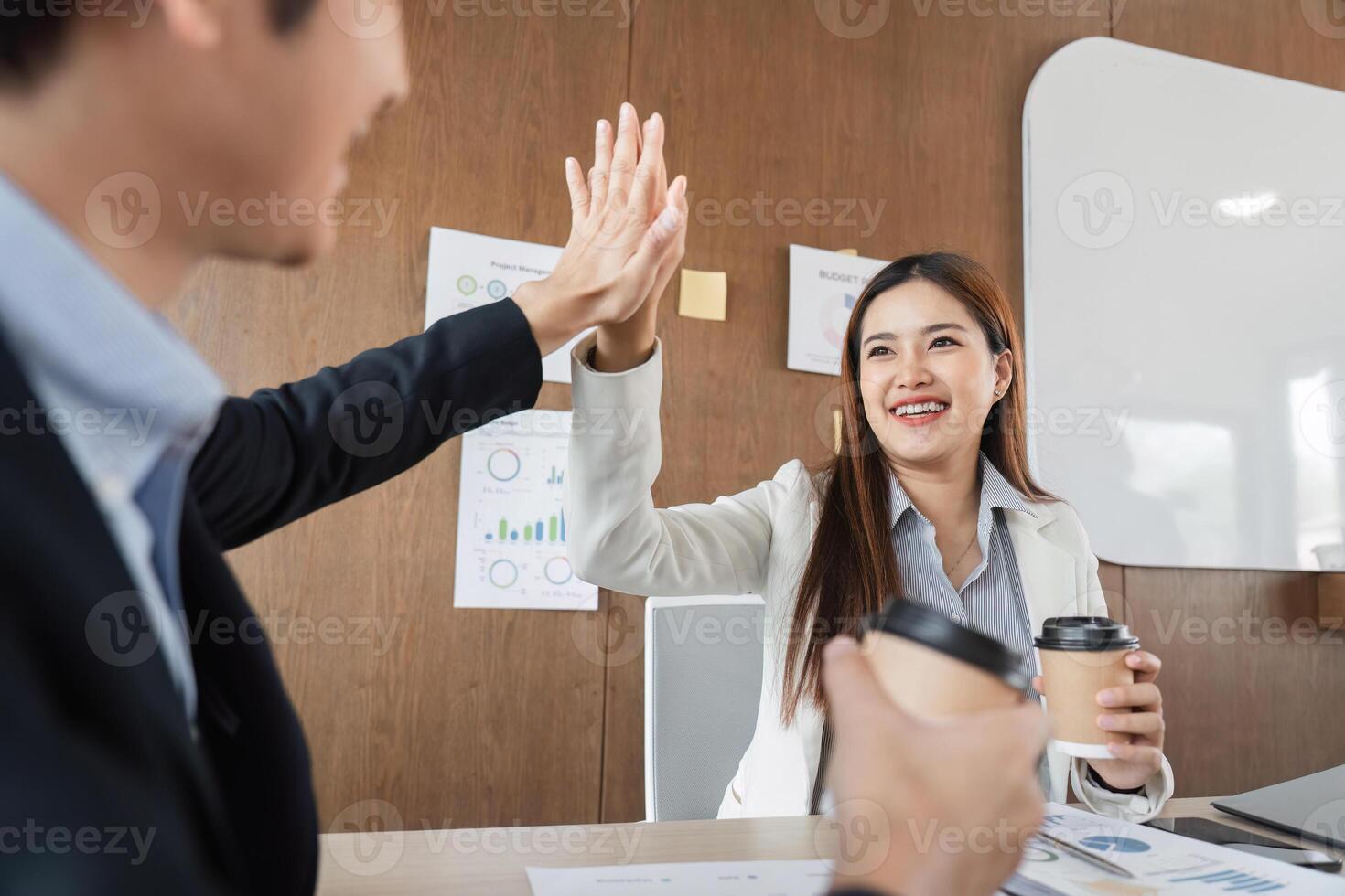 Teamwork and Celebration. A business team member celebrating success with a high-five in a modern office. photo