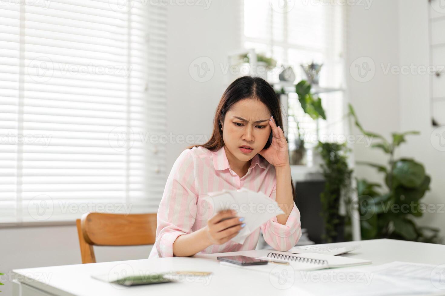Financial Stress and Remote Work. A woman feeling overwhelmed while sorting through bills at her home office. photo