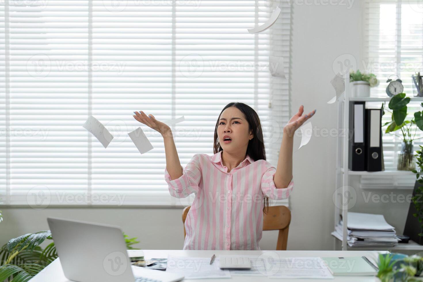 Frustration and Chaos in Finance. A woman expresses frustration while throwing away papers in her home office. photo