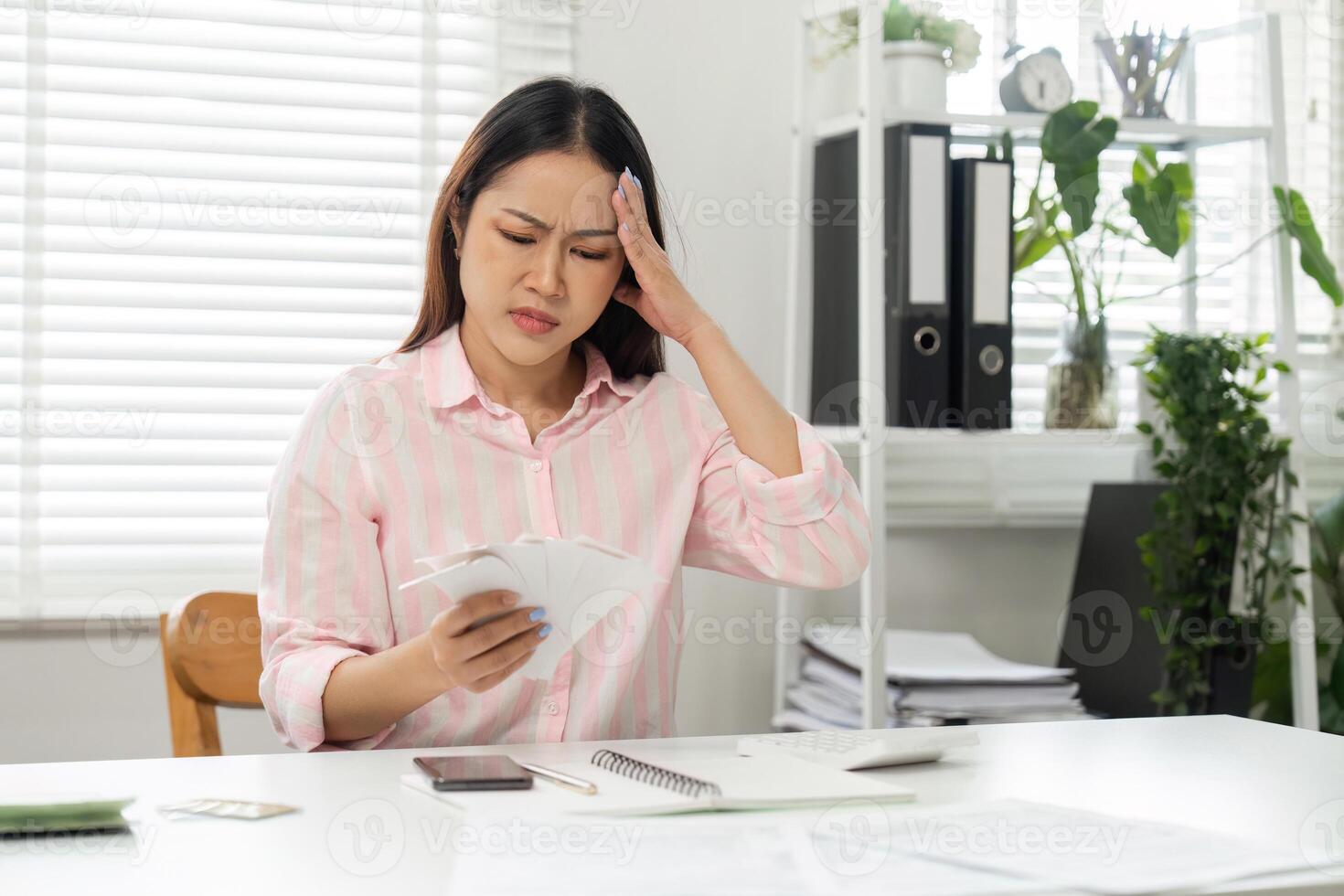 Home Office and Budget Anxiety. A woman feels overwhelmed while assessing her financial documents at home, juggling responsibilities. photo