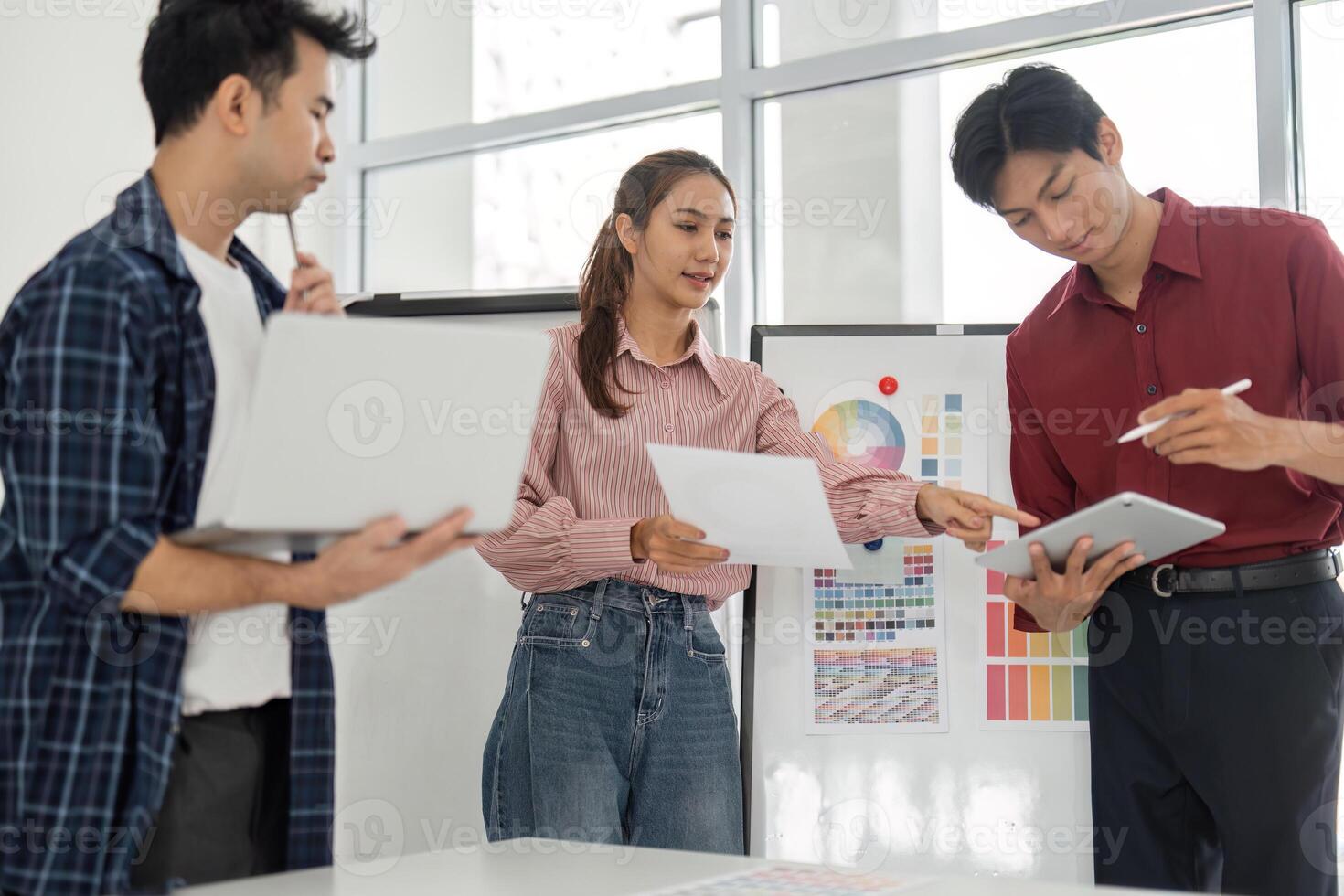 Collaboration and Color Choices. A designer discusses color palettes while a colleague documents ideas on a laptop. photo
