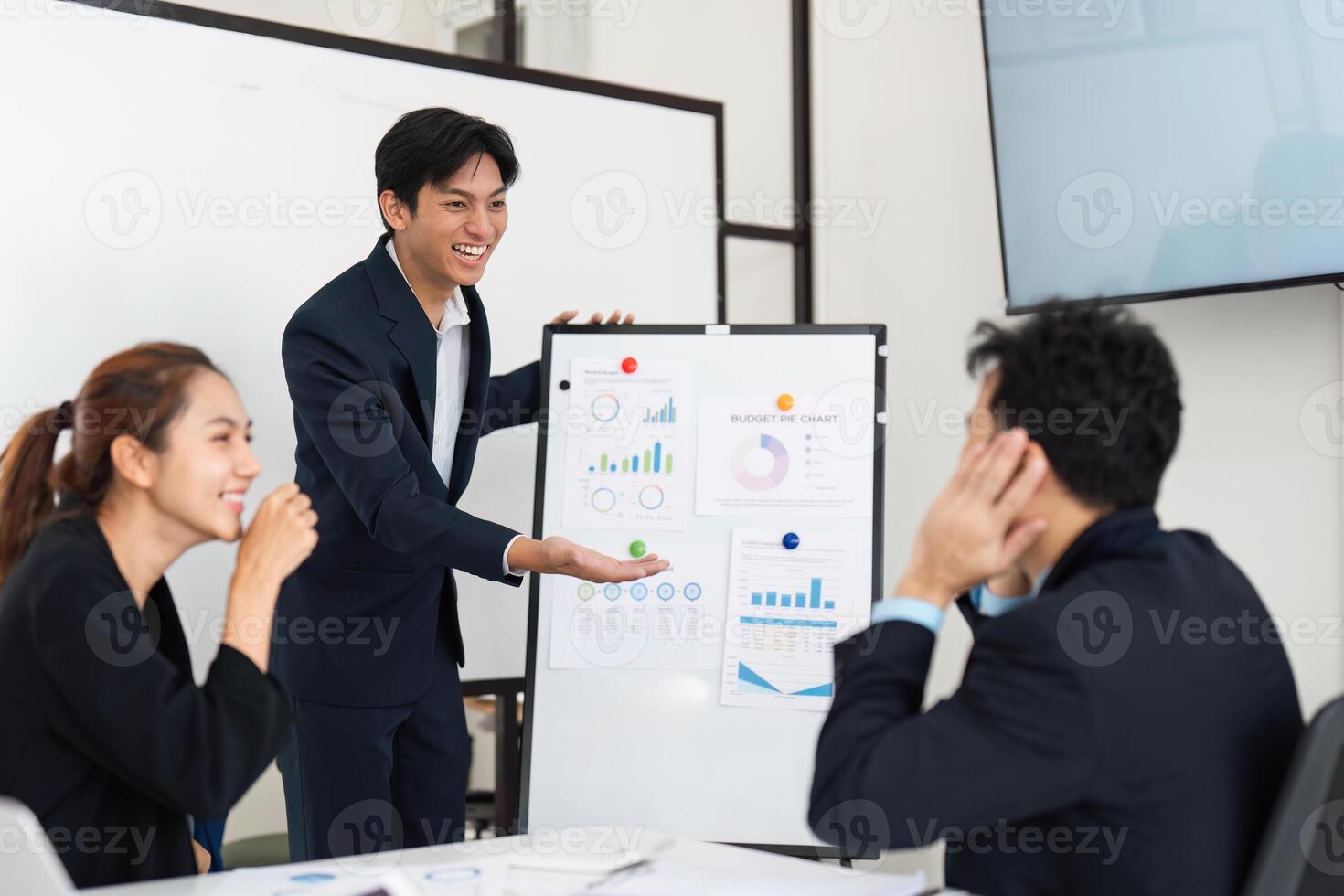 Enthusiastic Presentation and Team Energy. A young man presents budget findings with excitement to his colleagues. photo