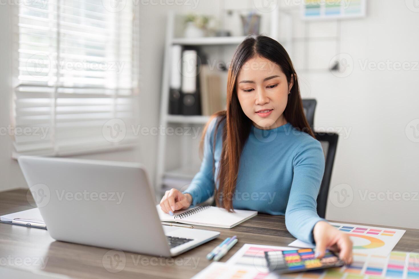 Creative Process and Color Selection. A designer contemplating color choices while working on her laptop. photo