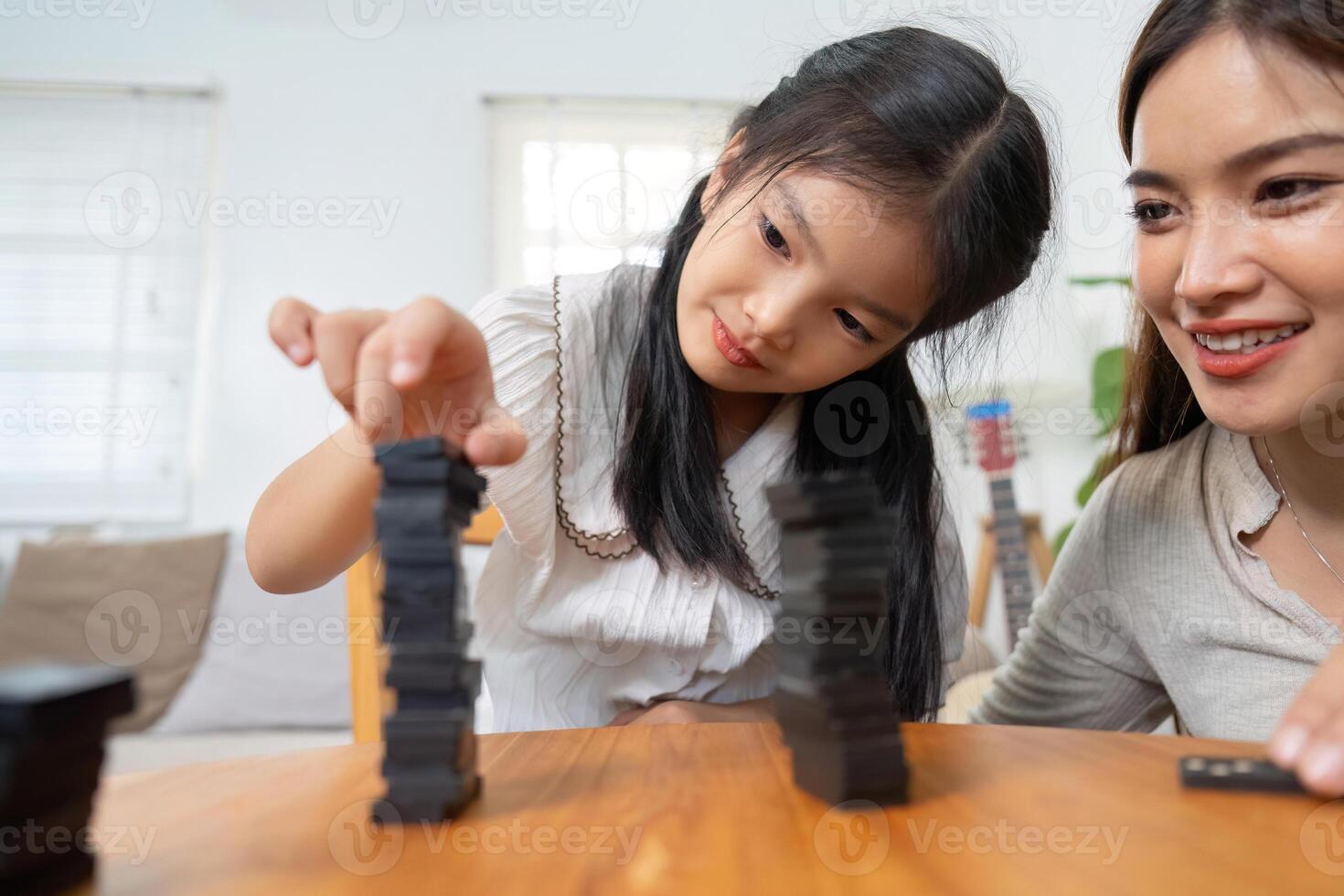Joy and Fun. The playful interaction between a mother and her daughter as they build and compete in a stacking game. photo