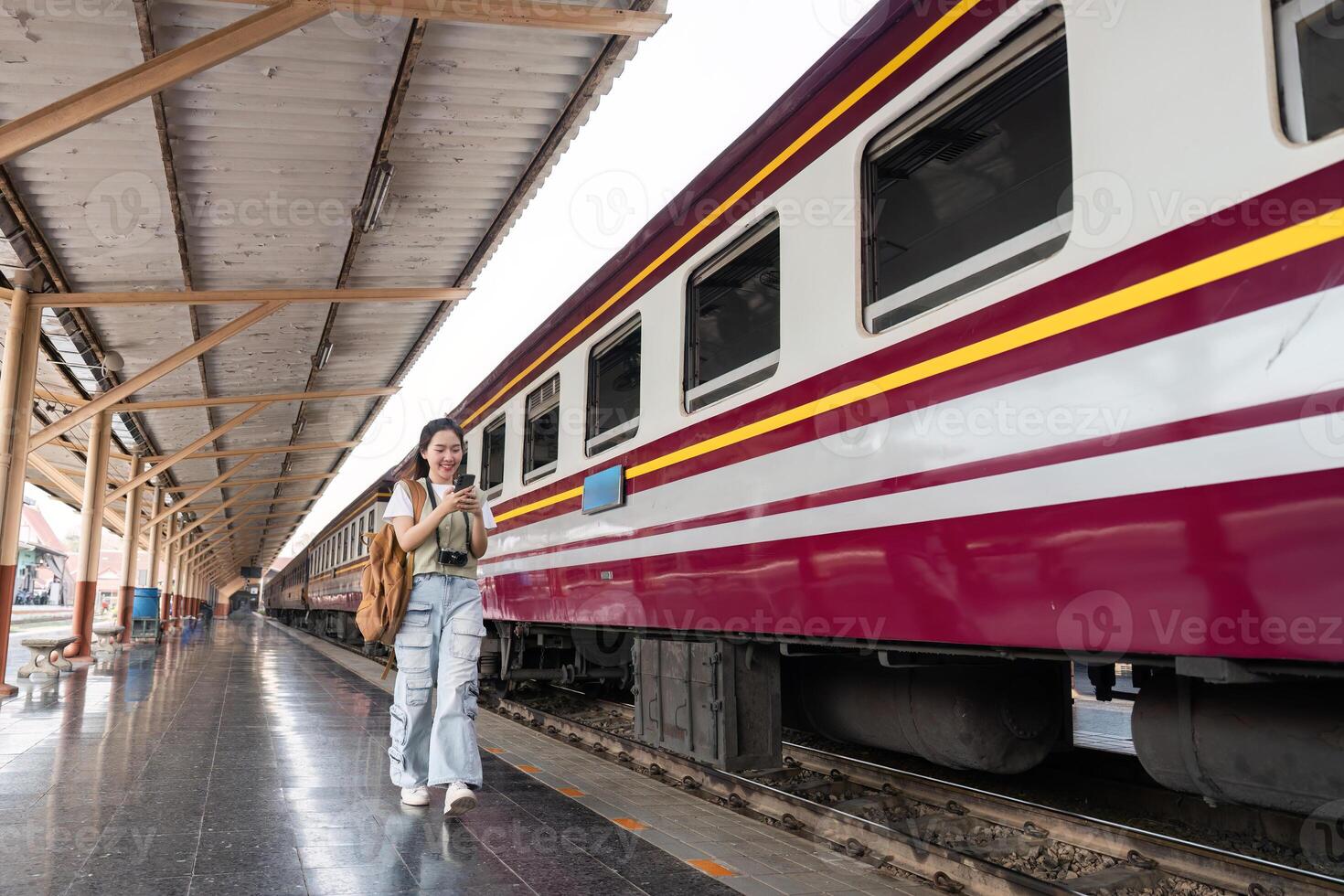 Traveling and Journeying. A stylish woman walking along the railway platform, engaged with her phone as she enters a new adventure. photo