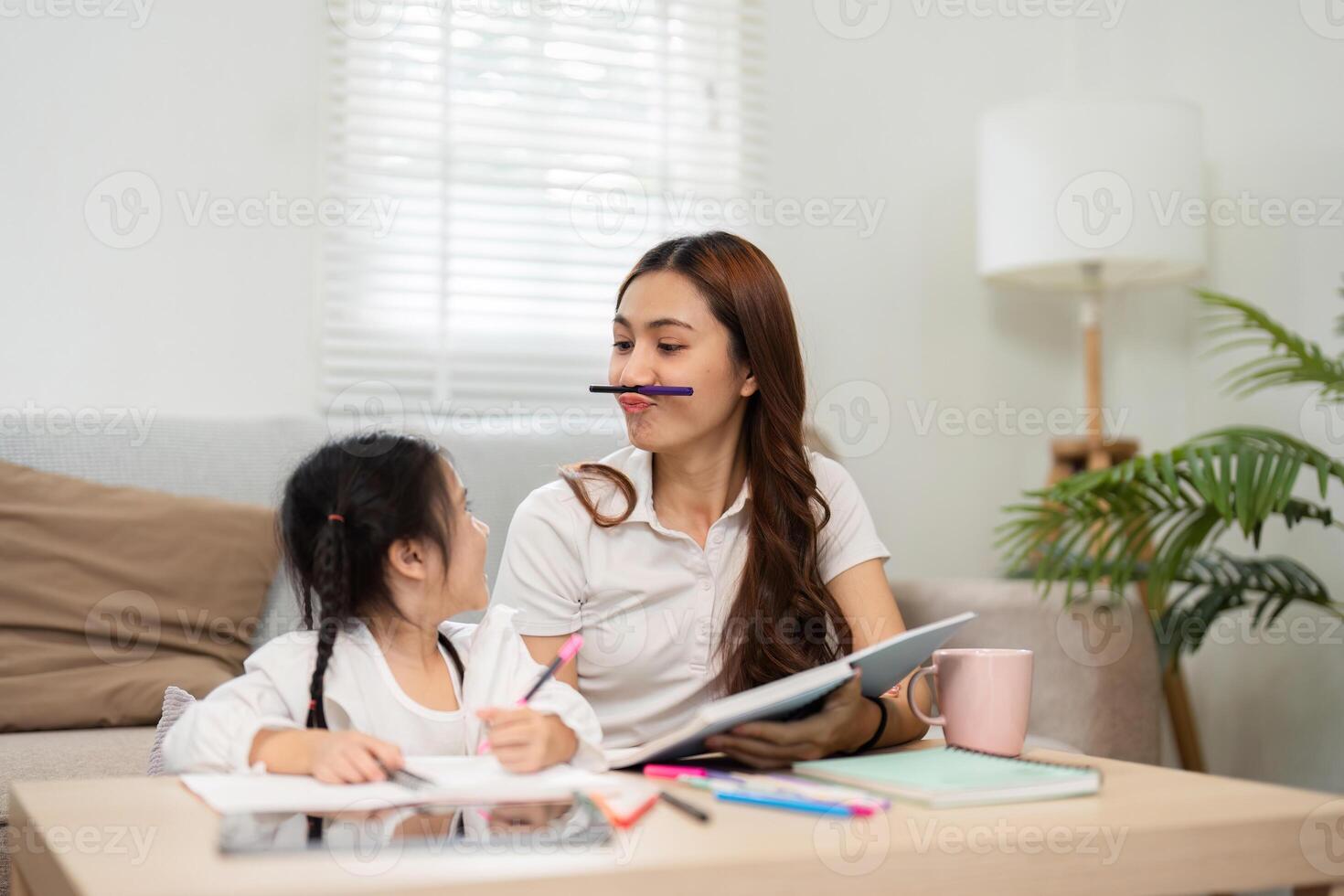 Playful Learning and Expressive Moments. A mother and daughter share laughter during study time. photo