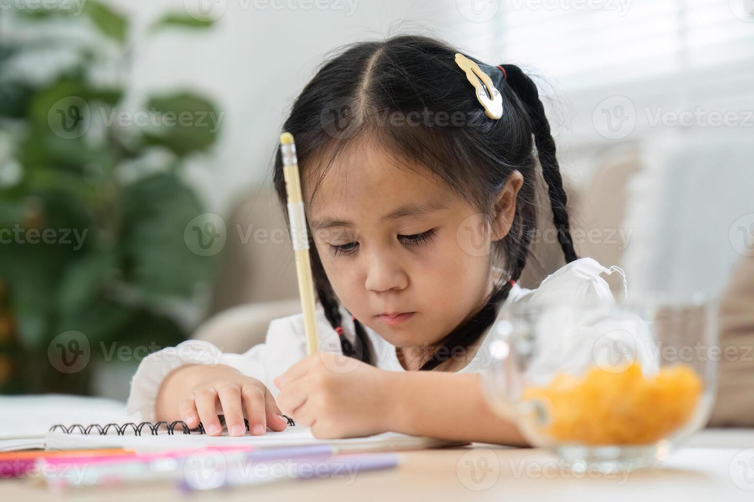 Back to School and Learning Fun. A focused girl studying on a notebook at home, practicing her writing skills. photo
