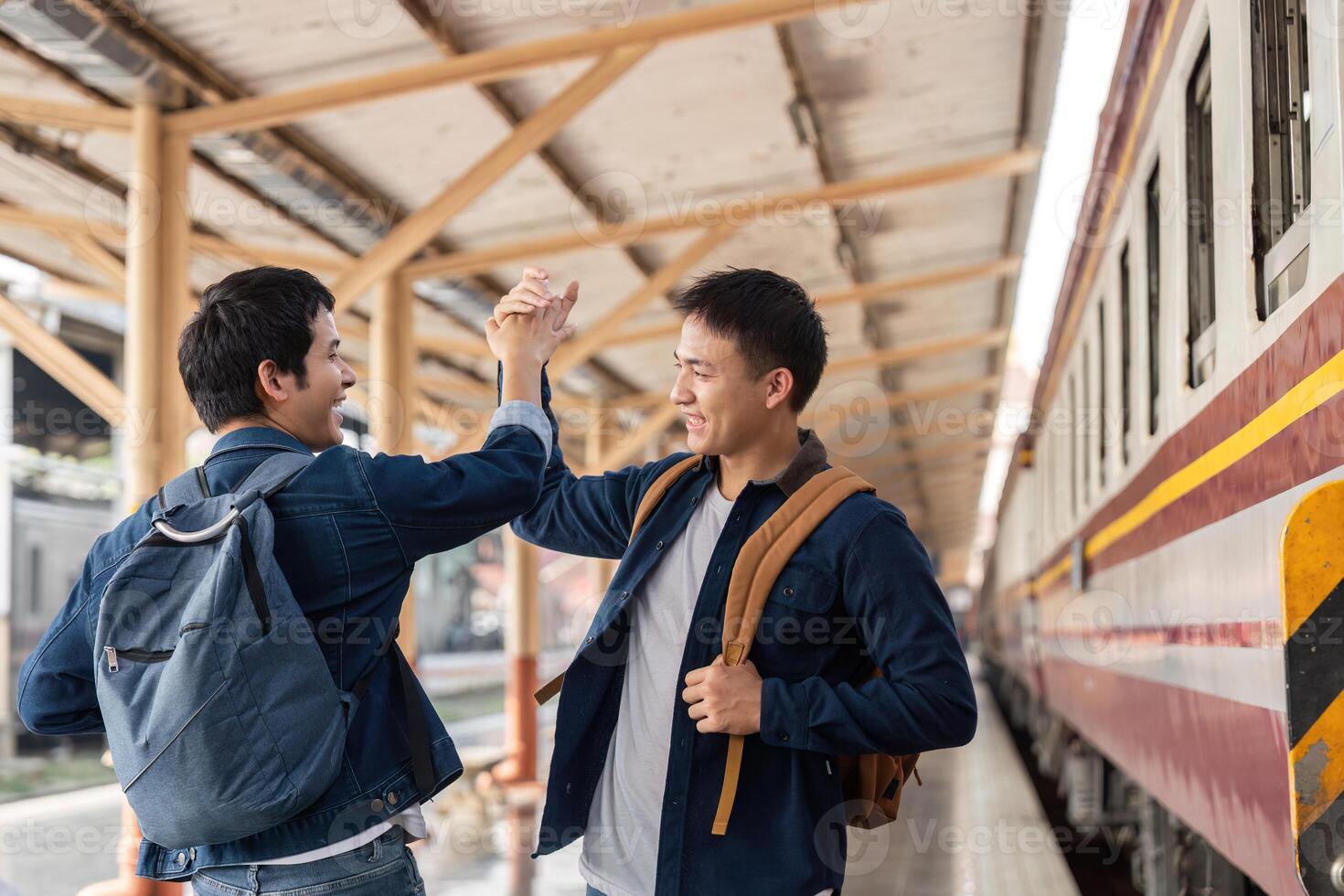 Celebrating Friendship and Travel. Two friends high-fiving at the train station excited about their adventure. photo