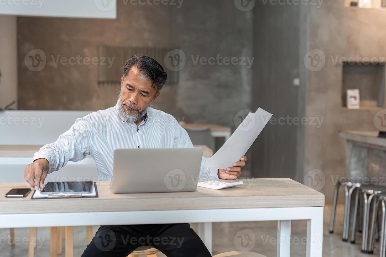 Engaged male businessman coordinating documents while using laptop in a sleek modern workspace photo