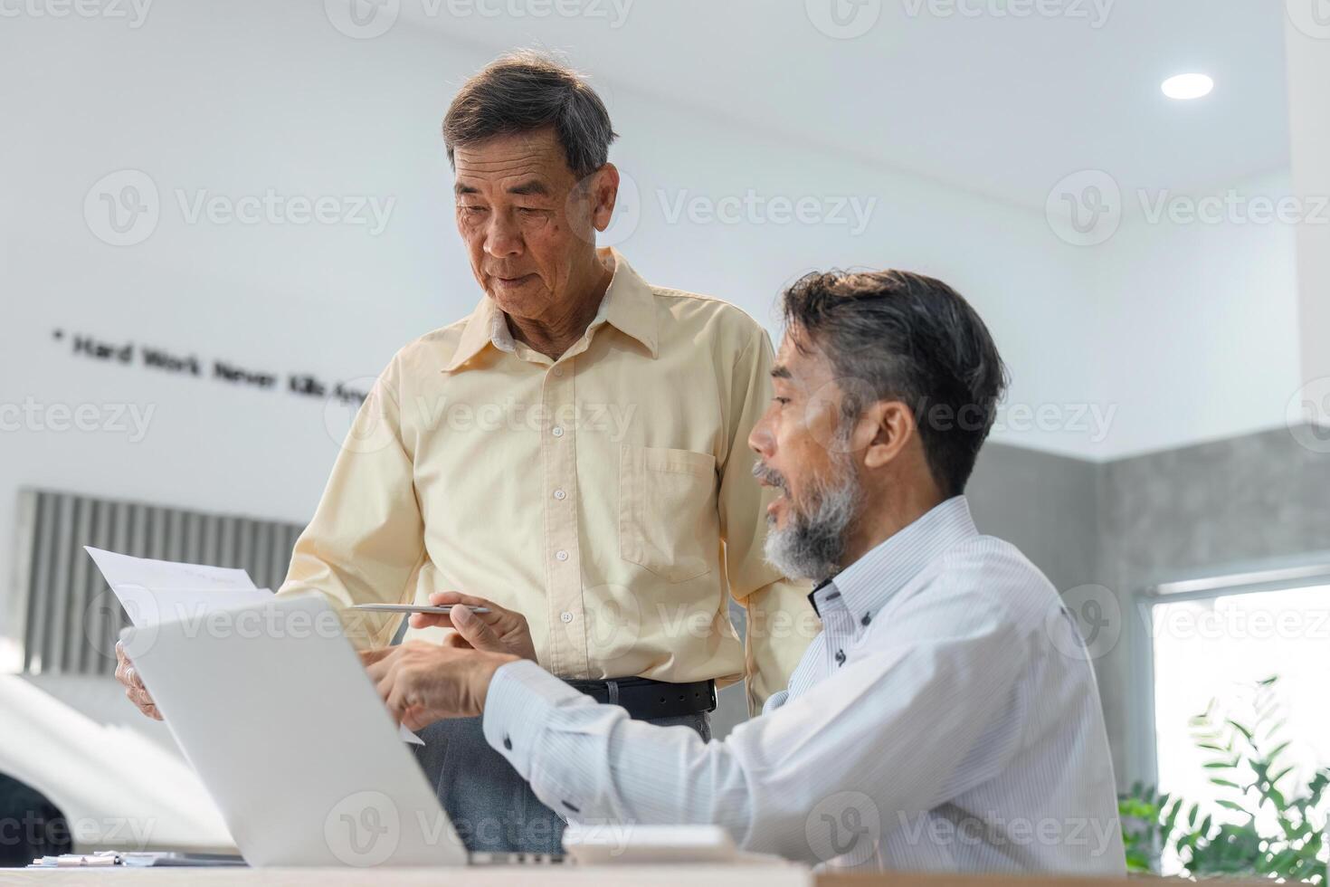 Seasoned businessmen discussing project updates while examining documents in a bright office environment photo